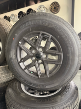 Load image into Gallery viewer, OEM '07-'26 Jeep Wrangler 17" Dark Charcoal Rims 245/75R17 Bridgestone HT Tires
